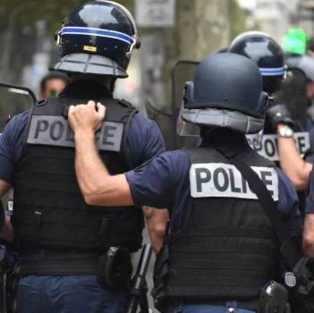 Des policiers en uniformes de la marine et portant des casques se tiennent ensemble, l'un avec une main de soutien sur le dos de l'autre, exprimant ainsi le travail d'équipe et la solidarité dans une rue de la ville.